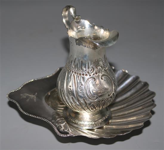 A Victorian silver cream jug and a George III butter shell.